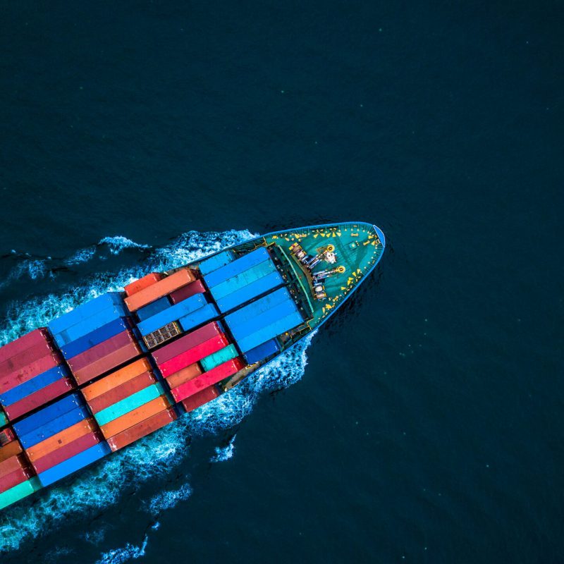 A freight-liner pictured from above as it cuts through an ocean, carrying shipping containers
